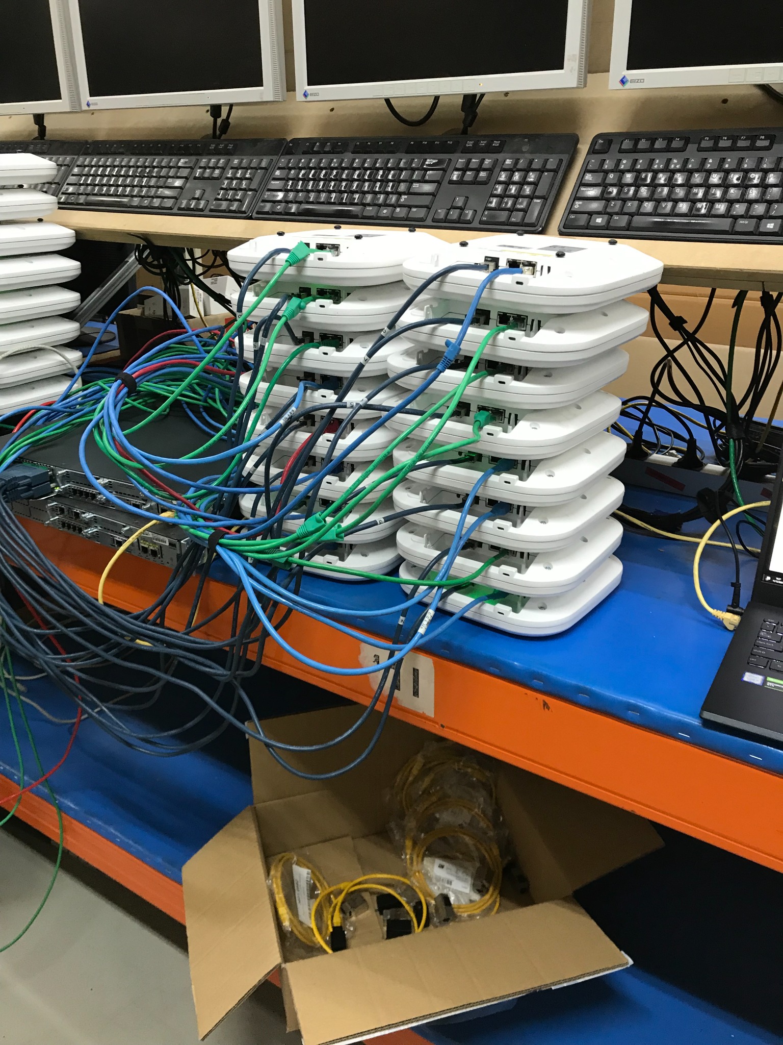 Stacked access points connected with network cables at a testing station